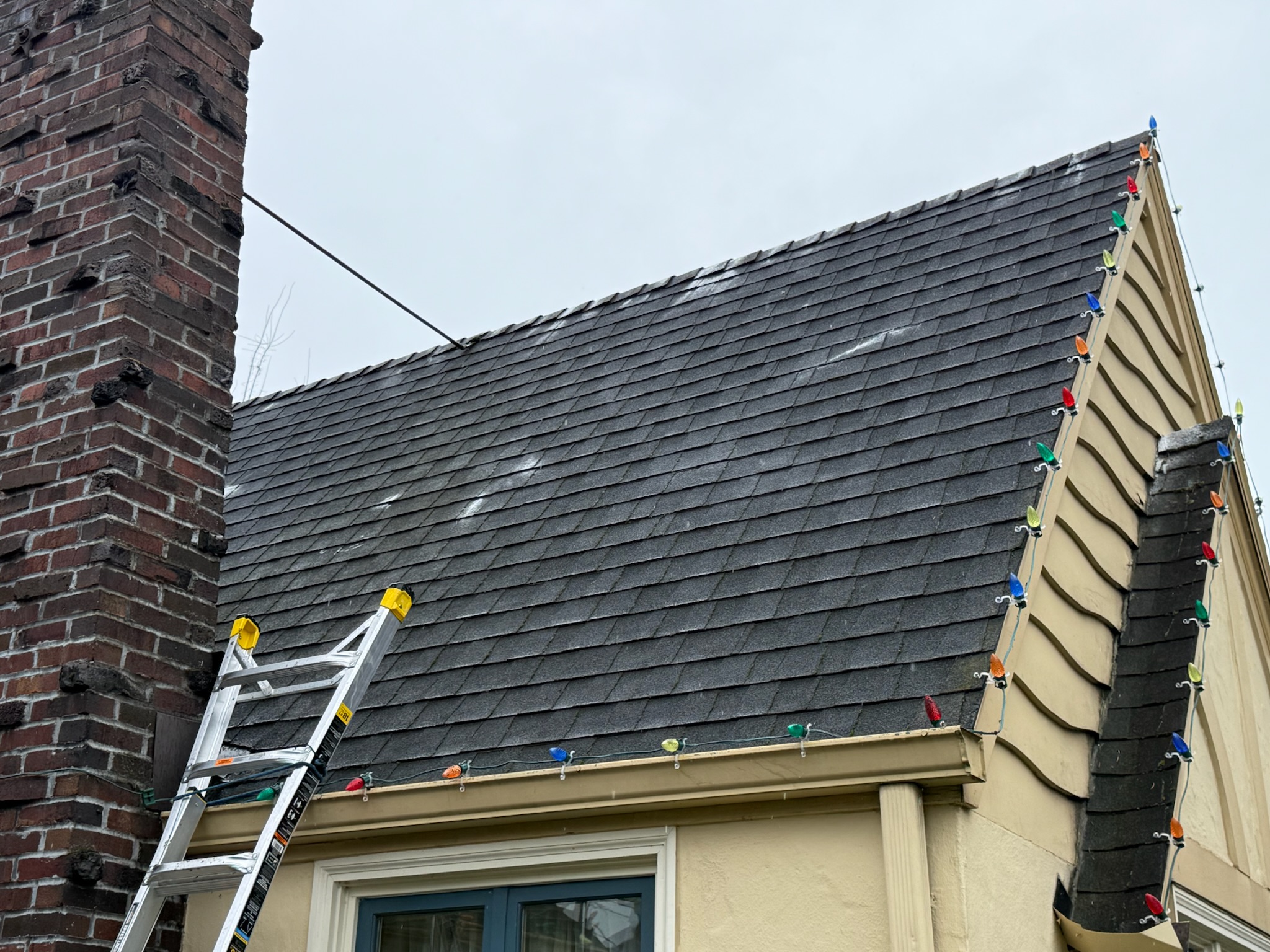Freshly cleaned slate roof with brick chimney after professional roof cleaning service