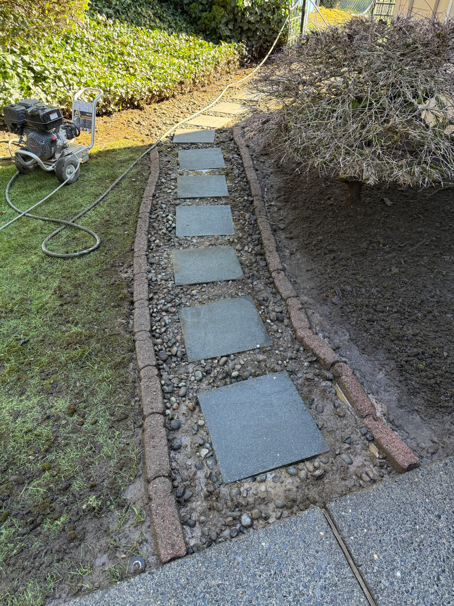 Stone stepping walkway with pressure washing equipment ready for cleaning service