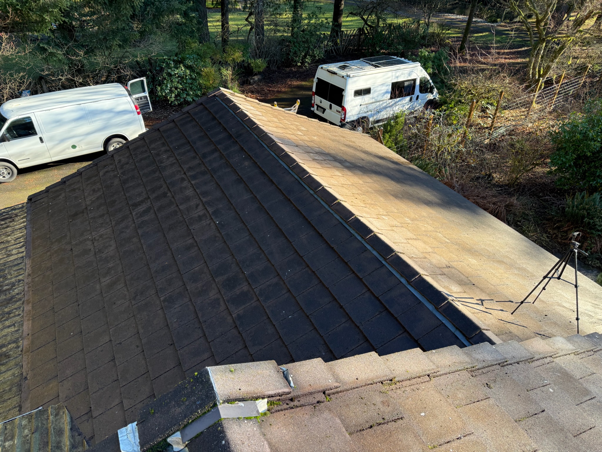 Roof half cleaned showing dramatic before and after difference with work vans on site in Vancouver WA